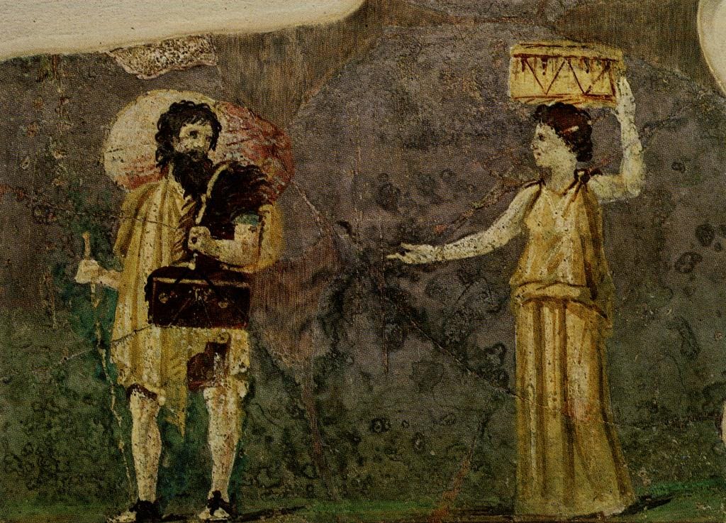 A faded Roman wall painting: a bearded man with a staff and a bag walks towards a young woman who carries a basket on her head.